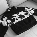 Black and white cow print jacket worn by a person on a light gray background