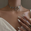 Close-up of a person wearing a unique silver necklace with a neutral background