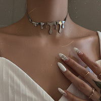 Close-up of a person wearing a unique silver necklace with a neutral background