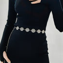 Black sweater with a decorative silver belt on a plain background