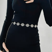 Black sweater with a decorative silver belt on a plain background