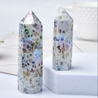 Two natural crystal stones with a blue rough texture, placed on a white surface with a decorative flower and a cup in the background.