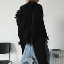 Person wearing a chunky knit black sweater with a blurred background