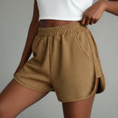 Brown shorts with a white graphic tee worn by a person in front of a gray background