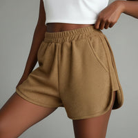 Brown shorts with a white graphic tee worn by a person in front of a gray background