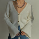 Person wearing a white cardigan over a blue top with a neutral background