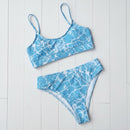 Blue and white marble patterned bikini set on a light wooden floor.