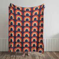 A Nordic cotton wool nap blanket with a colorful geometric pattern, draped over a chair in a cozy setting.