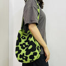 Person holding a green and black patterned bag against a white background