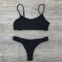 Black bikini set on a wooden surface with a starfish.