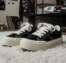 Black sneakers with white soles on a metal bench, featuring 'Fashion Lauridsen' branding.