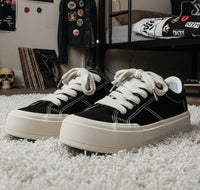 Black sneakers with white soles on a metal bench, featuring 'Fashion Lauridsen' branding.