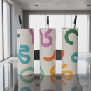 Three cylindrical tumblers with colorful abstract patterns and black straws on a white background