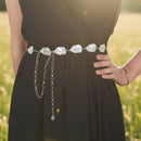 Black dress with a decorative silver belt featuring leaf designs on a natural background