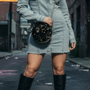 Person wearing a denim dress and black knee-high boots on an urban street.