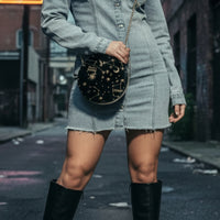 Person wearing a denim dress and black knee-high boots on an urban street.