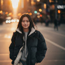 Person wearing a black puffer jacket with white lining on a plain background