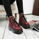 A pair of women's round toe front lace up boots in a wine red color, with high-tops and lace-up closure.
