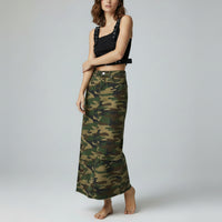 Woman wearing a black top and camouflage skirt on a gray background