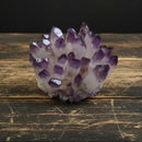 A hand holding a natural crystal cluster ornament with a sparkling, faceted surface.