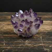 A hand holding a natural crystal cluster ornament with a sparkling, faceted surface.