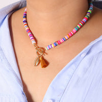 Colorful beaded necklace with a tassel pendant on a person wearing a light blue shirt.