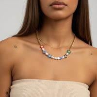 Necklace with colorful flower-shaped pendants on a model wearing a beige top.