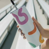 Tumbler with colorful design held by a hand on a white background
