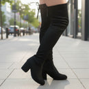 Black knee-high boots with a block heel on a white background