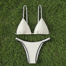 White bikini set with black accents on grass