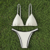 White bikini set with black accents on grass
