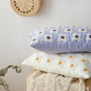 Two floral-patterned cushions stacked on a wooden surface with a light background.