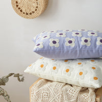 Two floral-patterned cushions stacked on a wooden surface with a light background.