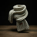 cream knitted scarf on display with a black background