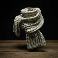 cream knitted scarf on display with a black background