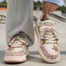 Person wearing white sneakers with star and heart designs on a blurred outdoor background