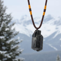 A black tourmaline pendant necklace with an orange rope.