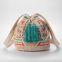 Crocheted bag with colorful patterns and green tassels on a light background