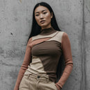 Woman wearing a brown and beige outfit against a concrete wall