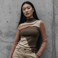 Woman wearing a brown and beige outfit against a concrete wall