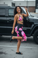 Black bikini set with pink floral design and matching skirt on a white background