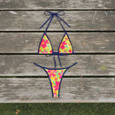 Colorful floral bikini set with a straw hat and framed picture on a white background
