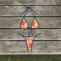 Colorful floral bikini set with a straw hat and framed picture on a white background