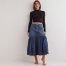 Person wearing a black crop top, blue denim skirt, and black boots against a white background