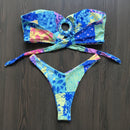 Colorful bikini set with floral patterns on a dark surface.
