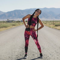 Woman in a colorful athletic outfit standing on a road with mountains in the background