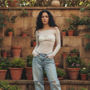 Woman standing in front of a stone wall with potted plants