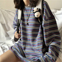 Person wearing a blue and white striped dress with a backpack and plush toy on a bed.