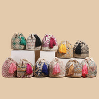 Collection of colorful woven bags with tassels on a beige background
