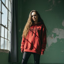 Person wearing a red hoodie standing in a room with green walls and a window.